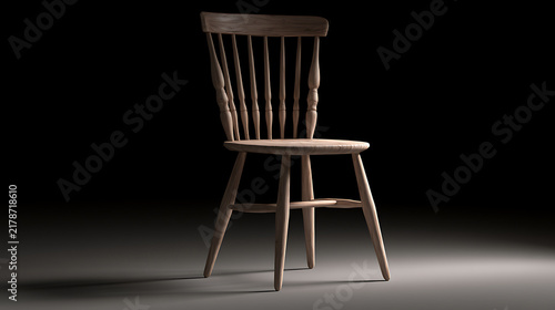 Wooden dining chair with spindle backrest stands against a dark backdrop