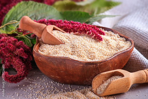 Amaranth grits in a wooden bowl with blooming branch amaranth, closeup with selective focus