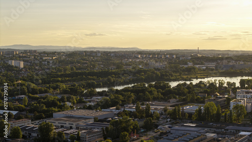 Aerial view of the Krakow cityscape featuring the Vistula river, lush greenery, and buildings under warm golden hour light in Krakow, Lesser Poland Voivode, Poland.