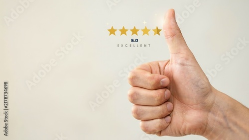 A person gives a thumbs up gesture with five stars and excellent rating hologram. This represents customer satisfaction and positive business feedback concept.