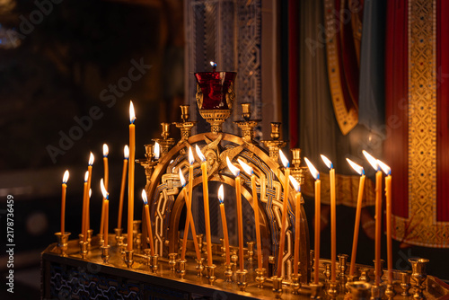 Foto Ceremonial candles line gilded stand and glow in dark religious room