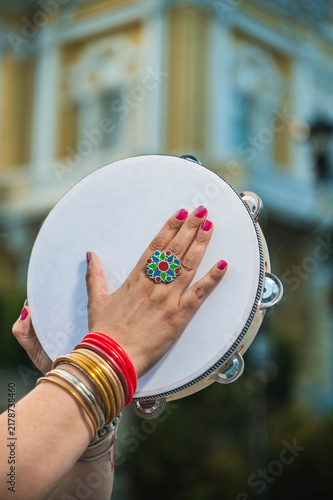 A sturdy Latina-Roma woman playing a tambourine and singing traditional Roma songs; in the background, the Regional Museum of Anthropology (Palacio Cantón) in Mérida, Yucatán, is visible.
