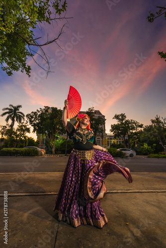 A sturdy Latina-Gypsy woman dancing traditional dances in the streets of Mérida, Yucatán, Mexico; the famous Regional Museum of Anthropology (Palacio Cantón) is visible in the background.
