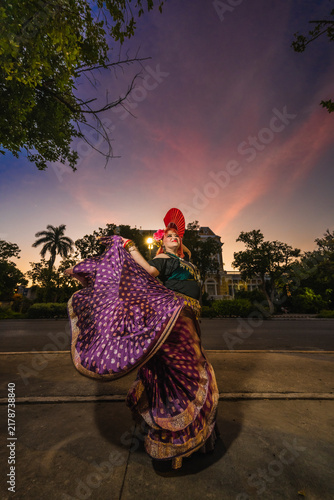 A sturdy Latina-Gypsy woman dancing traditional dances in the streets of Mérida, Yucatán, Mexico; the famous Regional Museum of Anthropology (Palacio Cantón) is visible in the background.
