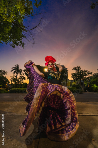 A sturdy Latina-Gypsy woman dancing traditional dances in the streets of Mérida, Yucatán, Mexico; the famous Regional Museum of Anthropology (Palacio Cantón) is visible in the background.
