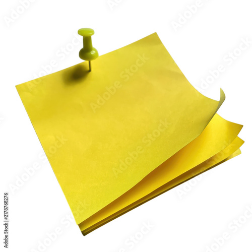 Bright yellow sticky note paper with a green plastic push pin attached for reminders in an office workplace