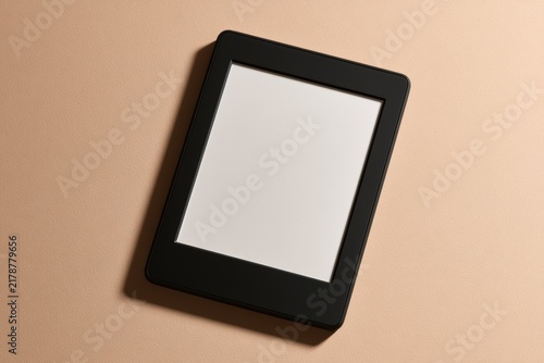 E-reader device displaying a blank white screen on a warm beige background