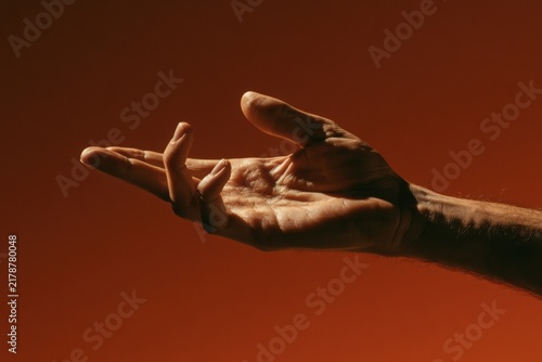 Human hand extending, seeking, or offering assistance against a warm, gradient background
