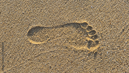 фотографія A single human footprint is clearly indented in the textured golden sand of a beach