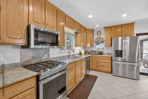 Warm wooden kitchen cabinets with stainless appliances  granite countertops sink faucet LED lighting