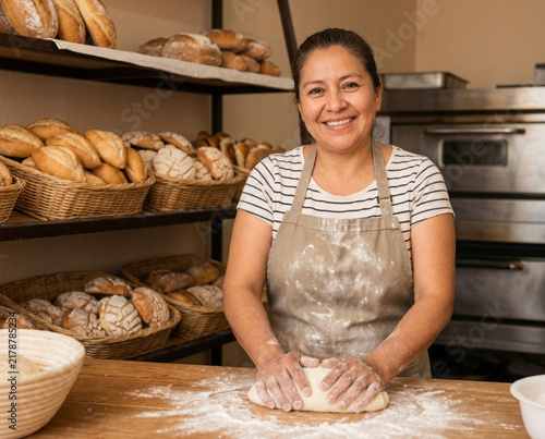 Smiling Baker Kneading Dough in Rustic Bakery Surrounded by Fresh Bread and Wicker Baskets