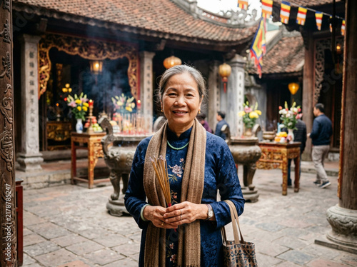 Elderly Vietnamese Woman Holding Incense in Ancient Temple Courtyard Wearing Traditional Áo Dài