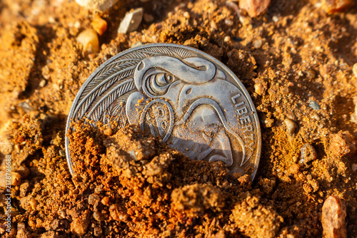 Obraz na plátně Vintage silver coin featuring a Native American profile half-buried in dry gritt
