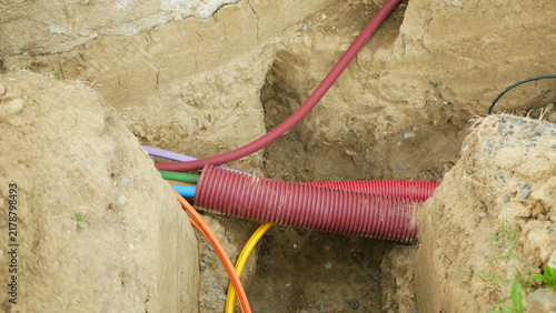 Fiber optic internet infrastructure cables copper engineering networks conduits laying installed underground excavated soil trench construction excavated digging routing pathway, protective placed