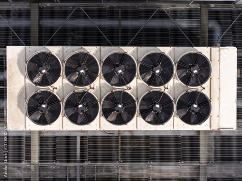 Aerial view of industrial HVAC cooling fans arranged in a grid on a metal rooftop in Gdansk, Poland.