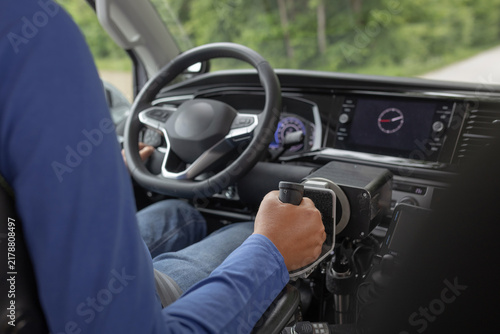 Obraz na płótnie A man with a disability drives a modified vehicle using hand controls on a road surrounded by trees