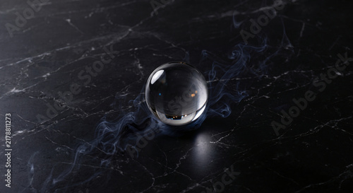 Glowing crystal ball with mystical smoke on black marble with negative space