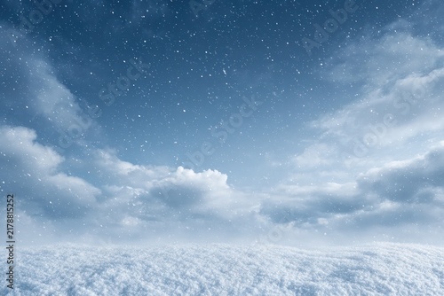 Snow-covered field under cloudy winter sky with falling snowflakes