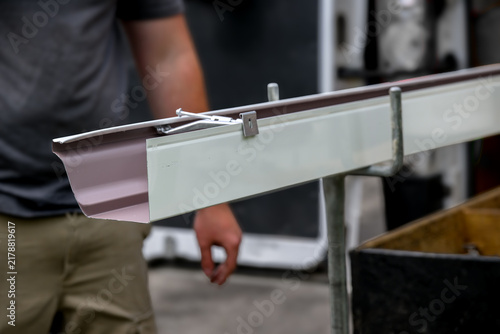 Technician extruding custom-made gutters for our home in Windsor, Upstate NY. The skilled hands of a craftsman preparing gutters for installation.