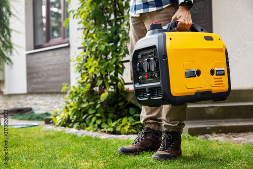 Man carrying portable generator for emergency home power supply