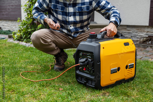 Man starting portable inverter generator for home backup power or outdoor electricity supply