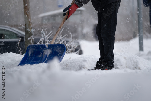Person Shoveling Snow on City Sidewalk During Winter Snowfall