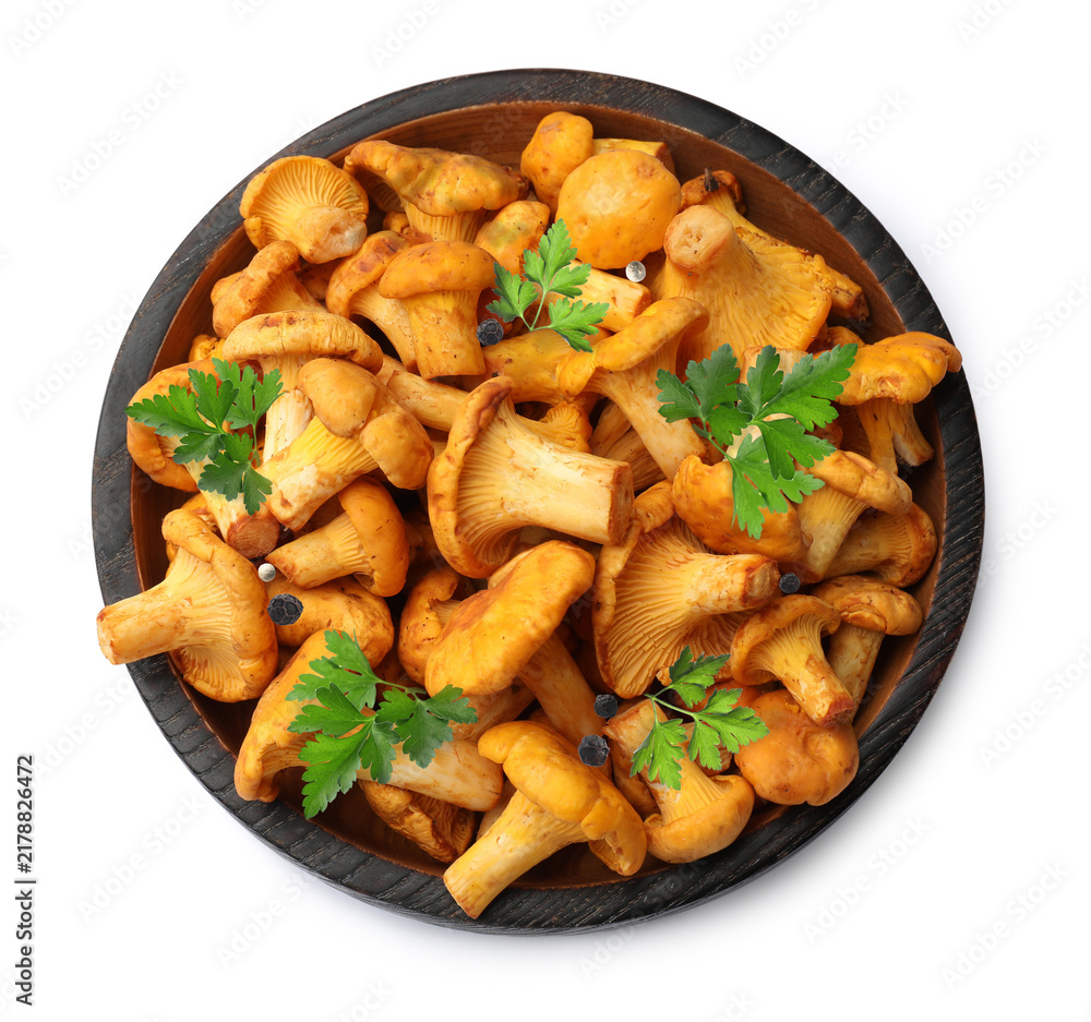 Obraz premium Fresh chanterelle mushrooms and green parsley leaves in bowl isolated on white, top view