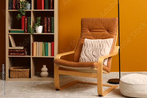 Blurred view of stylish home library with brown armchair and bookshelf