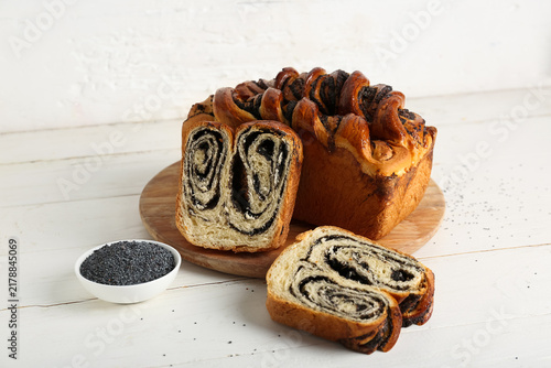 Quadro su tela Board with sweet poppy seed roll on white wooden background