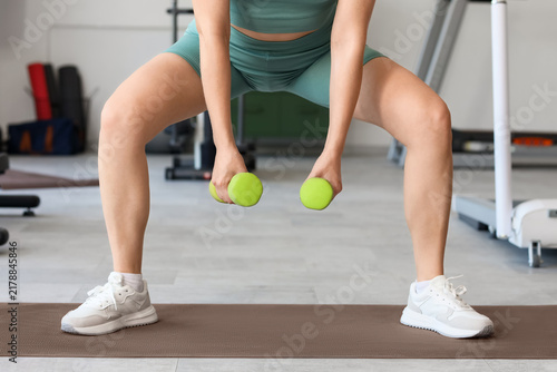 Obraz na płótnie Fitness and strength training, woman doing squats with dumbbells in gym for heal