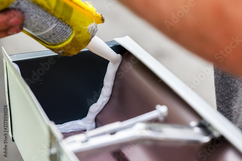 A technician's hands installing custom-made gutters on our home in Windsor, Upstate NY. The skilled hands of a craftsman preparing gutters for installation.