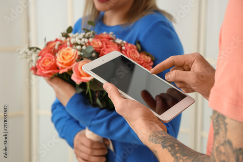 Young woman receiving bouquet of flowers from courier at door, closeup