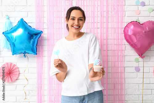 Beautiful happy pregnant woman with delicious cupcake and question mark on wh...