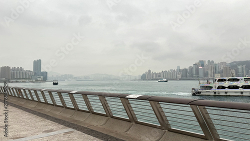Waterfront promenade promenade overlooking city and water, in urban waterfront with modern buildings, with promenade railing, water, city skyline, boats, with concrete, metal, glass texture.