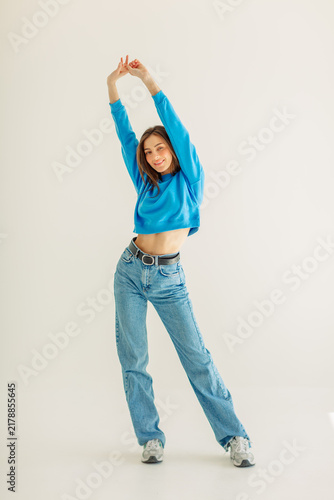 Young woman dancing with crossed legs and raised arms
