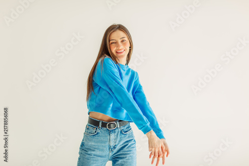 Young woman turning with an arm out in a blue sweatshirt
