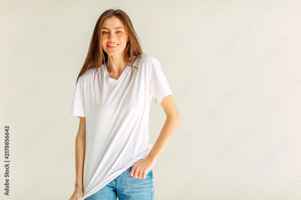 Obraz premium Smiling young woman in a white t shirt in a wide frame