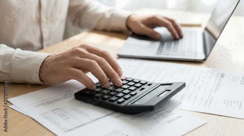 Businessman utilizing a web service for electronic tax declaration forms while calculating commercial costs and invoices.