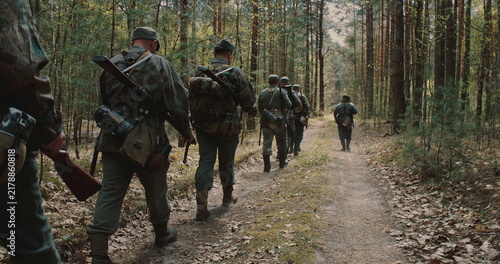 Photography Squad of WWII German infantry soldiers marching through spring forest