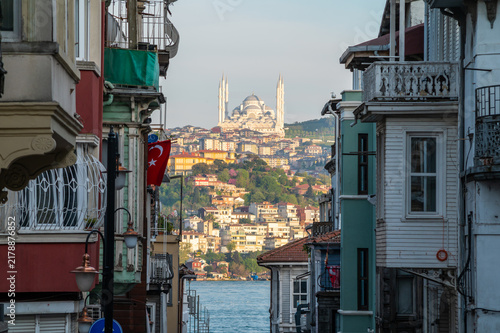 Old town street leads to waterfront with mosque on hill