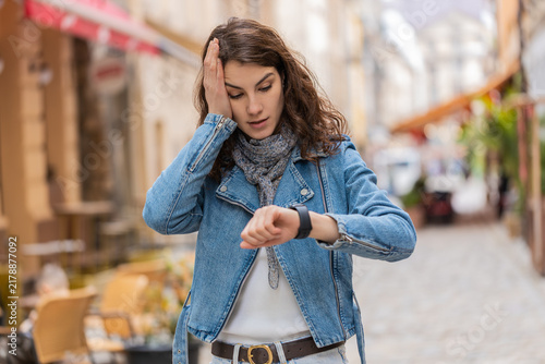 Foto Young woman checking wristwatch walking in city street feels worried about late meeting