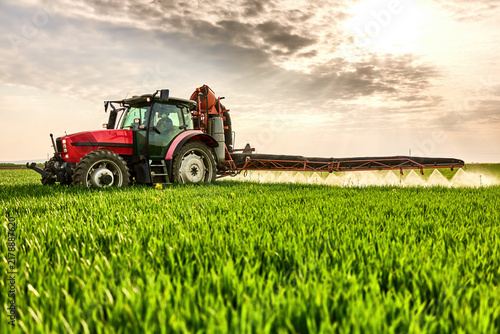 Tractor spraying agricultural field with chemicals, protecting crops for a good harvest