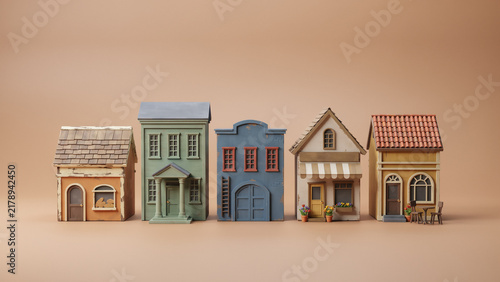 Miniature toy house models lined up on beige background