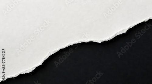 Close up of torn white ripped paper edge revealing black background for modern abstract design and banner concept presentation