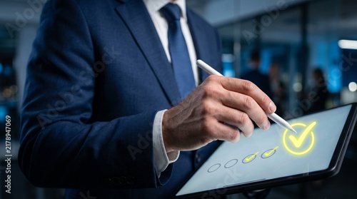Digital Checklist Confirmation: A businessman in a sharp suit uses a stylus to mark a checkmark on a digital checklist displayed on a tablet, symbolizing task completion and efficient workflow.
