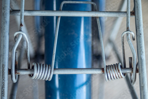 Close up of vintage bicycle rear rack with steel spring clip mechanism.A detailed top-down shot focusing on the spring-loaded cargo clip mechanism of a vintage bicycle rear carrier rack. 