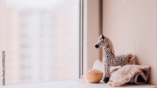 Spotted ceramic horse figurine with bowl of oats and folded linen cloth on countertop, home decor concept
