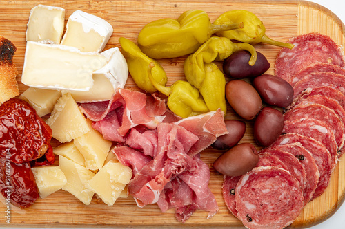 фотографія Cheese and meats are arranged on a wooden cutting board for a snack platter