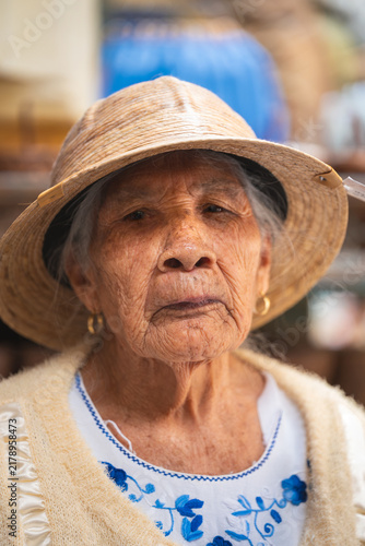 Foto Close up of an old senior woman with weathered skin and a straw hat looking to t