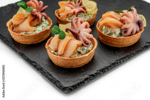 Konstfotografi Seafood tartlets with smoked fish and octopus served on a black slate